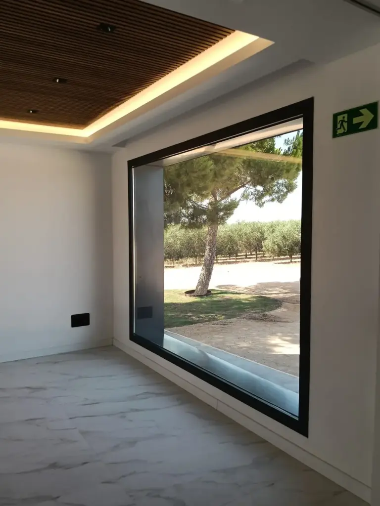 Sala de catas de aceite de oliva virgen extra con ventanal panorámico abierto a los olivos de Pagos de Aherca