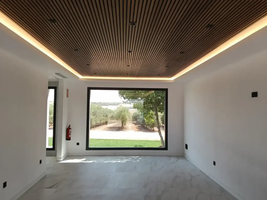 Interior de la sala de catas de Pagos de Aherca con techo de madera y gran ventanal con vistas al olivar
